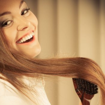 Health beauty and haircare concept - Closeup young business woman refreshing her hairstyle she brushing her long brown hair with wooden brush
